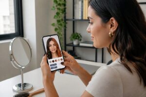 Brazilian woman using a smartphone app to preview different hair colors on her selfie at a desk